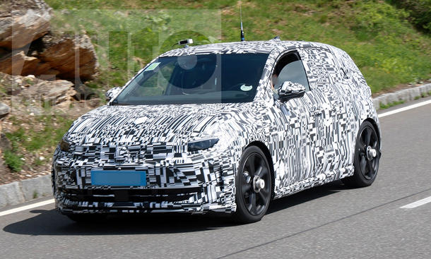 Der VW ID.2 GTI (2026) fährt als Erlkönig auf einer Landstraße, von vorne links fotografiert.