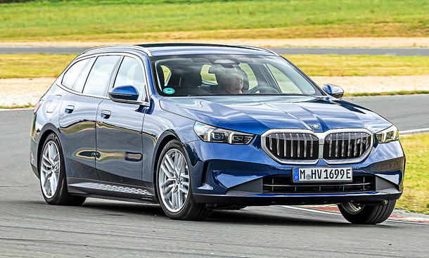 Blick von schräg vorne auf den fahrenden BMW i5 Touring.