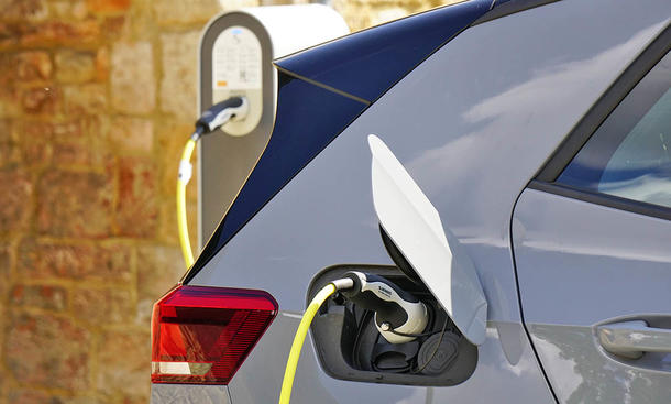 Ein Ausschnitt eines E-Autos, das mit dem Kabel verbunden ist und lädt.