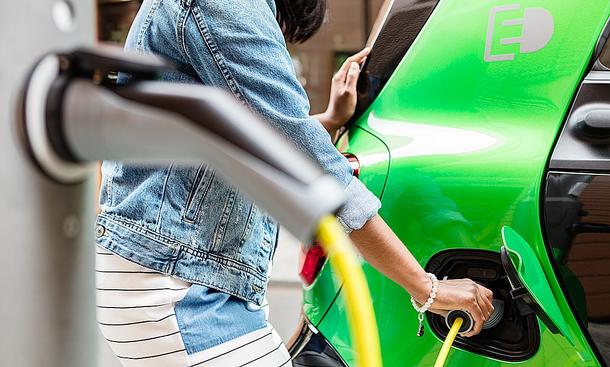 Eine Frau steckt ihr Elektroauto zum Laden an.