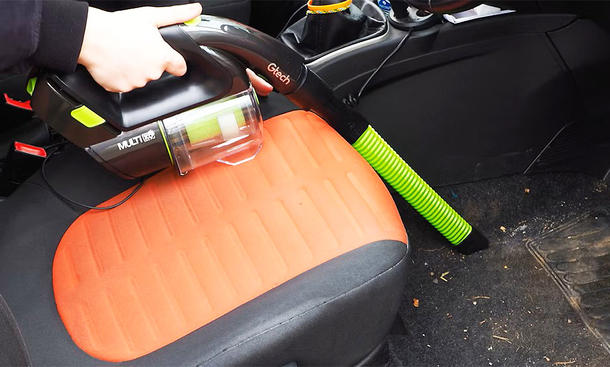 Der Handsauger Gtech Multi MK2 K9 beim Aussaugen eines Fußraums im Auto.