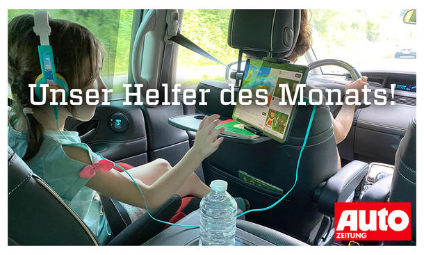 Mädchen auf der Rücksitzbank eines Autos beim Bedienen eines Tablets in einer Tablet-Halterung, fotografiert von hinten mit Blick auf Mädchen und Person am Steuer.