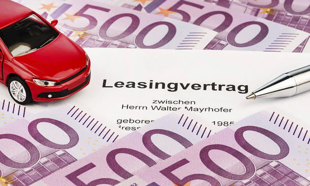Ein Leasingvertrag für ein Auto, daneben sieht man Geldscheine und ein kleines Miniatur-Auto.