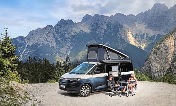Camping-Reise durch Slowenien im VW T7 California; stehend, Ansicht schräg vorne, Campingmöbel sind aufgebaut, Alpenpanorama