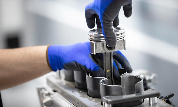 Eine Detailaufnahme zeigt wie an einem 2,0-l-Vierzylinder von AMG ein Kolben montiert wird.